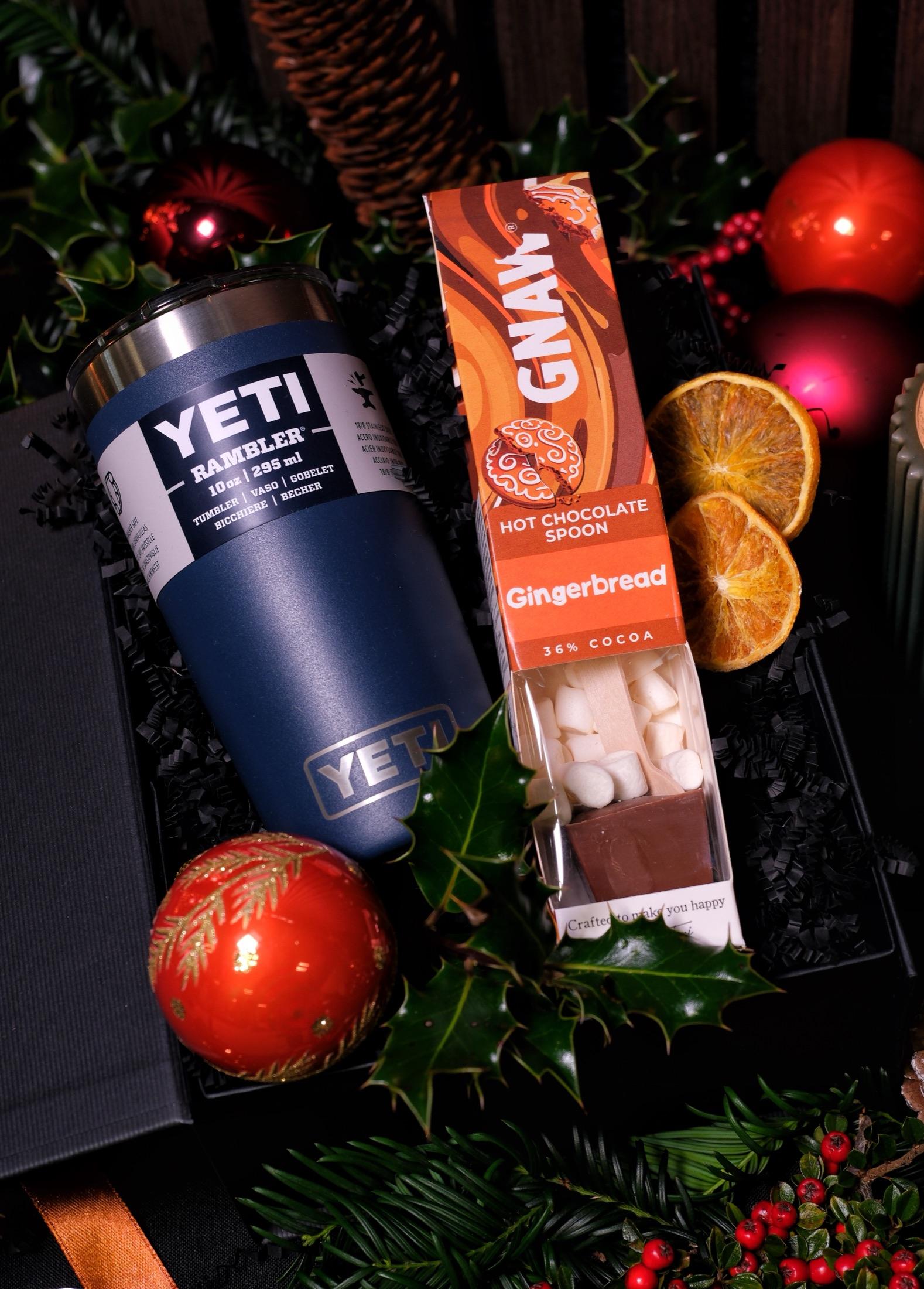 Navy insulated tumbler and a gingerbread hot chocolate spoon in a gift box with holly, baubles and dried orange