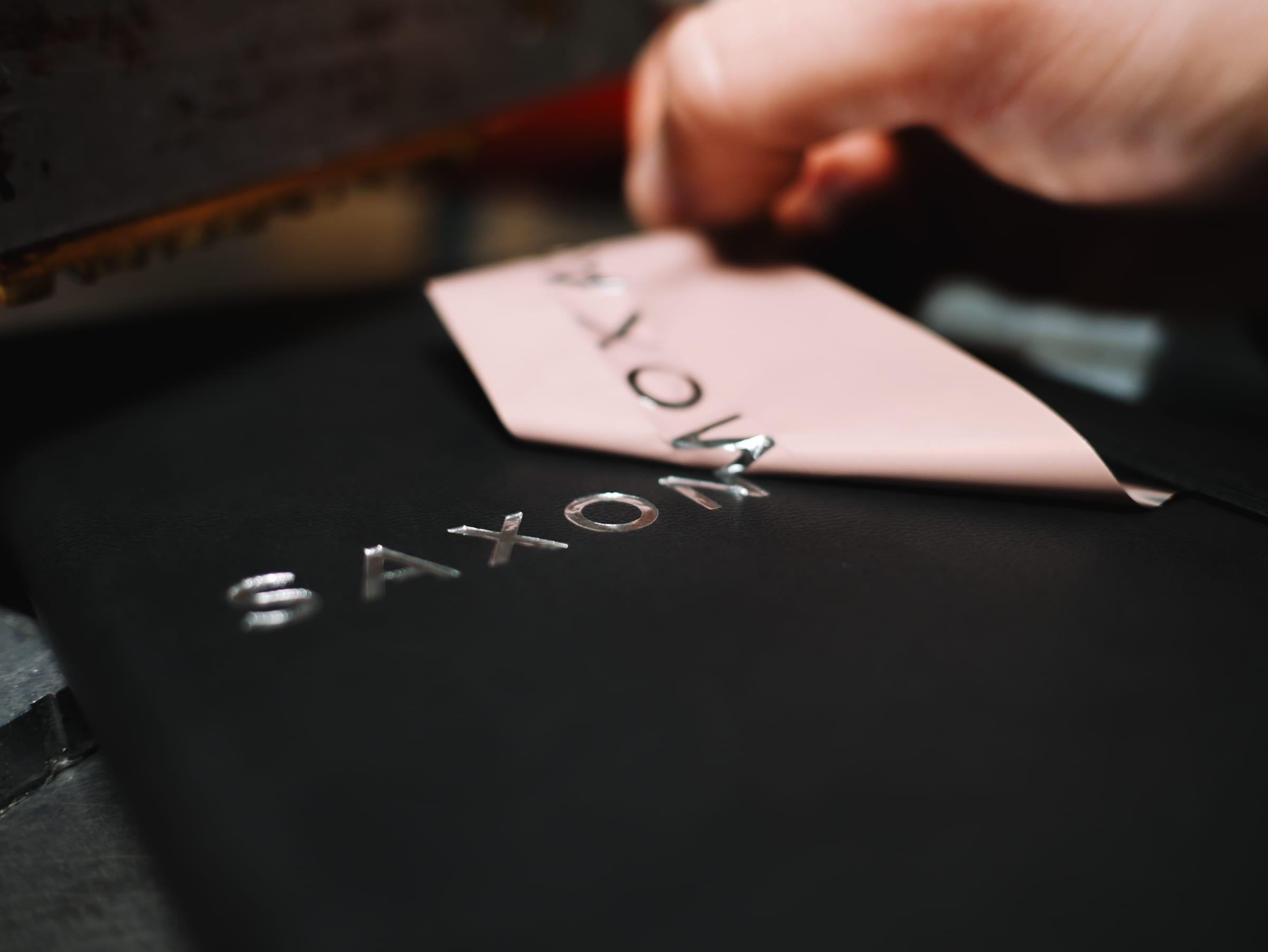 Saxon Air logo being foil stamped onto a black notebook cover